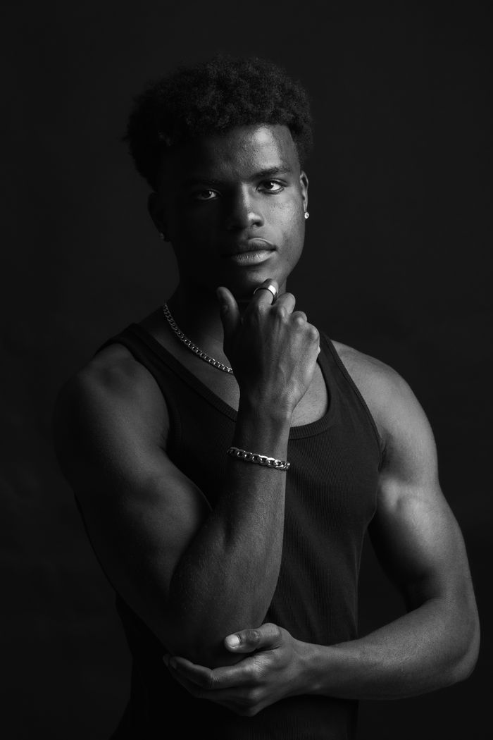 Black and white studio portrait of a thoughtful man posing with confidence and elegance.