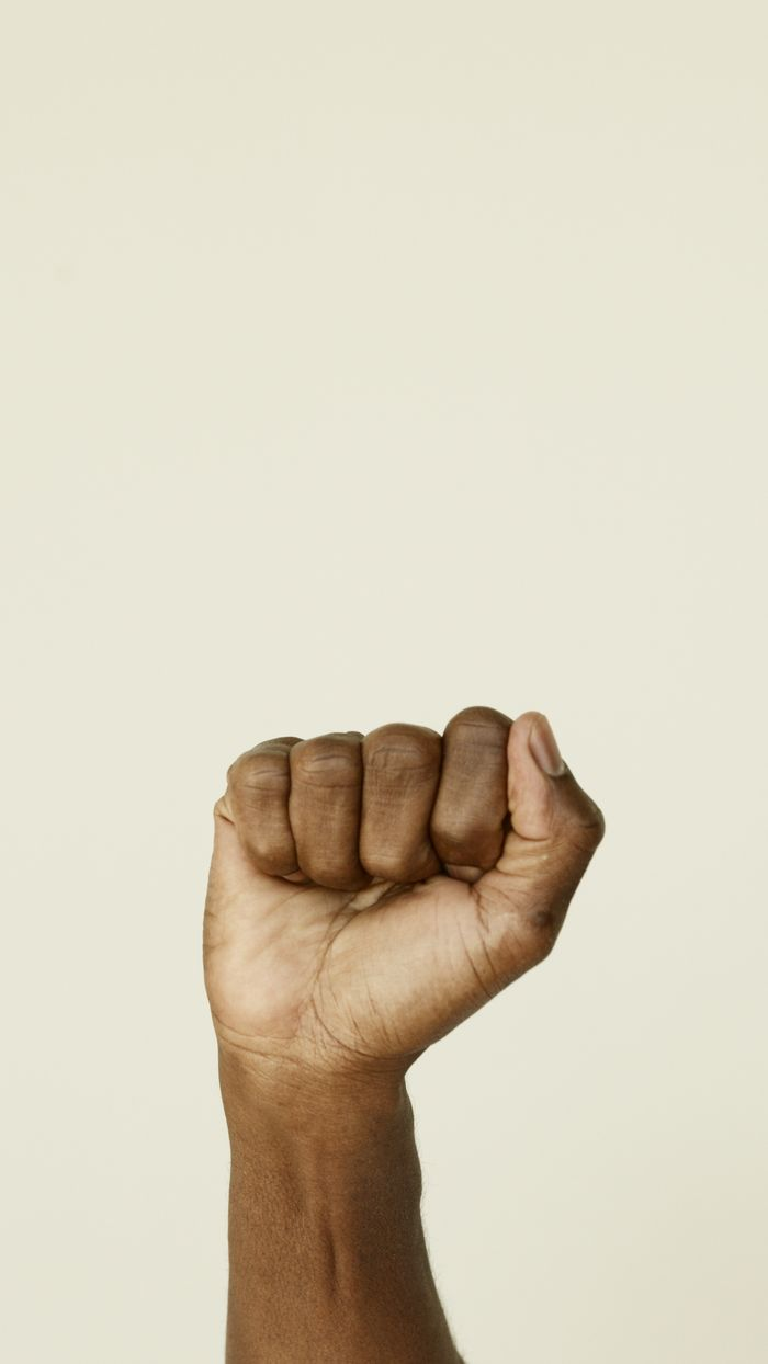 Close-up of a clenched fist symbolizing strength and unity on a light background.